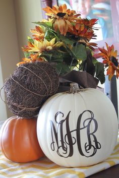 two pumpkins with monogrammed letters sit on a table