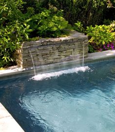 a small pool with a waterfall in the middle and water running down it's side