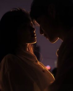 a man and woman standing next to each other in front of a building at night