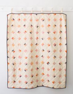 an orange and white quilt hanging on a wall