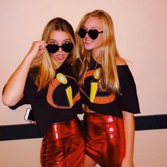 two beautiful young women standing next to each other wearing black sunglasses and red leather skirts