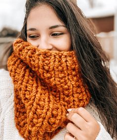 a woman with long brown hair wearing a knitted scarf