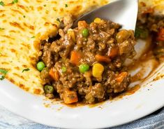 a white plate topped with meat and veggies covered in gravy next to quesadilla