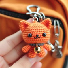 a small crocheted cat keychain hanging from a handbag with it's eyes open