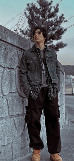 a man standing next to a stone wall