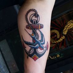 an anchor tattoo on the leg of a person's arm, with rope around it