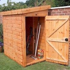 a wooden shed with its doors open and tools in the outside area next to it