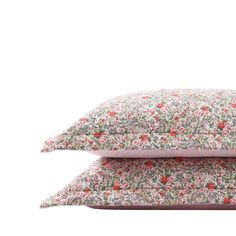 two pillows sitting on top of each other with pink and green floral print, one in the middle