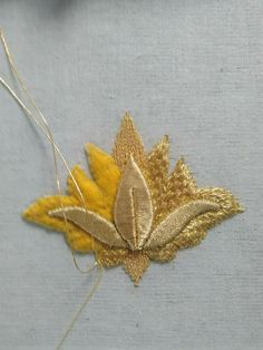 a close up of a piece of cloth with a leaf on it and thread in the middle