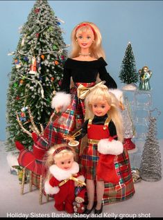 two dolls are posed next to a christmas tree