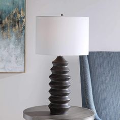 a lamp sitting on top of a table next to a blue chair with a white lampshade