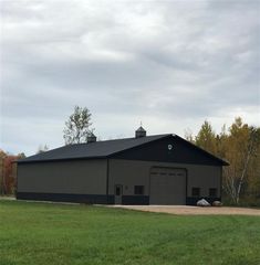 a large black barn sitting on top of a lush green field