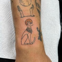 a small tattoo on the wrist of a person with a dog in front of them