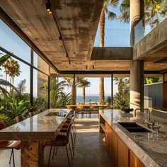 an open kitchen and dining area with palm trees in the background, overlooking the ocean