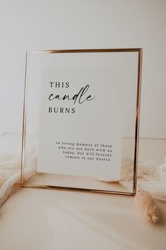 this candle burns sign is placed on a white surface with a gold frame and tassel