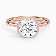 a rose gold engagement ring with a round cut diamond in the center, on a white background