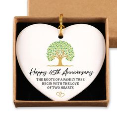 a white heart shaped ornament with a tree on it in a gift box