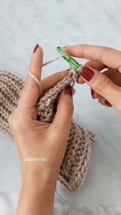 the woman is working on her crochet project with one hand and two fingers