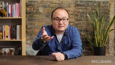 a man sitting at a table pointing to something