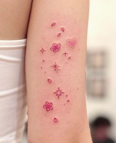 a woman's arm with pink tattoos on it and hearts, stars, and flowers