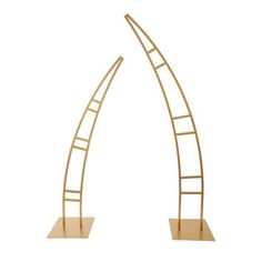 a pair of gold metal sculptures with wooden bases and curved ends, on white background