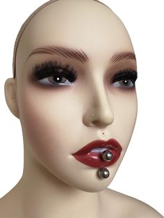 a mannequin head with red lipstick and piercings on it's nose