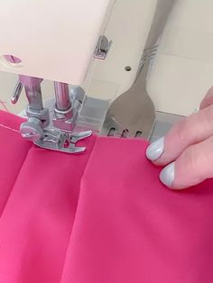 a person using a sewing machine to sew on a pink fabric with scissors in the background