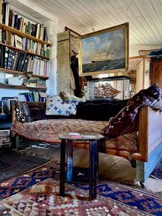 a living room filled with furniture and bookshelves next to a painting on the wall