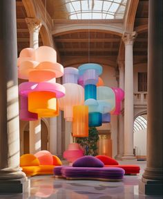 a room filled with lots of different colored lamps hanging from the ceiling and columns in front of it