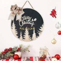 a merry christmas sign hanging from the side of a white wall next to red and silver ornaments