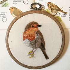 a cross stitch bird is sitting on top of a wooden frame with other birds in the background