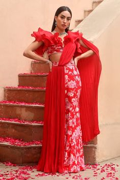 a woman in a red and white dress standing next to stairs with rose petals on the ground