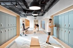 two men standing in the middle of lockers and looking at something on the wall