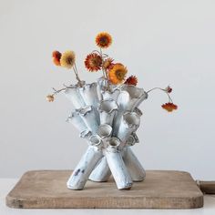 a metal vase with flowers in it sitting on a wooden table next to a white wall