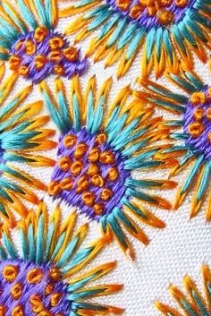 an embroidered piece with many colorful flowers on it's sides and purple, orange, and yellow centers