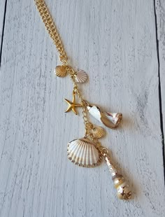 a gold necklace with shells, starfish and seashells hanging from it's chain