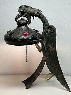 an old fashioned lamp with wings and a bird on it's head, sitting on a table