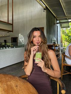 a woman sitting at a table with a drink in her hand