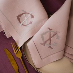 pink napkins with silver monogrammed letters on them and gold forks next to each other