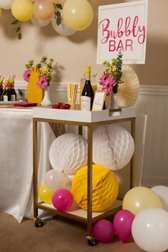 a table topped with balloons and bottles of wine next to a sign that says bubbly bar