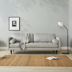 a white couch sitting on top of a wooden floor next to a lamp and rug