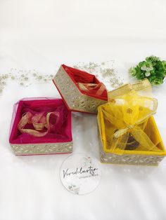 three different colored boxes with bows on them