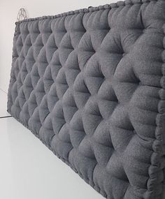 a close up view of a bed headboard made out of grey fabric with ruffled edges