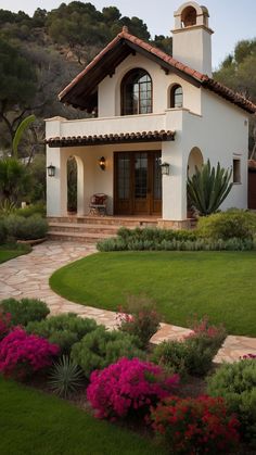 a white house with pink flowers in the front yard