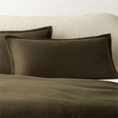 a bed with green sheets and pillows on it