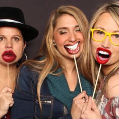 three beautiful women posing for the camera with their mouths open and holding sticks in front of them