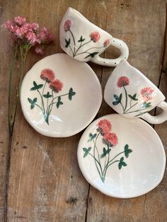 three white dishes with pink flowers on them