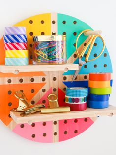 the craft supplies are organized on the wooden shelf in front of the colorful circle wall