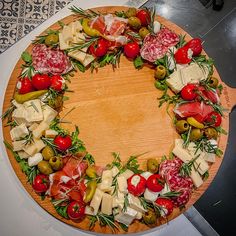 a wooden platter filled with lots of different types of cheese and toppings on top of a table