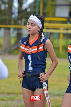 two girls in sports uniforms are standing on the field